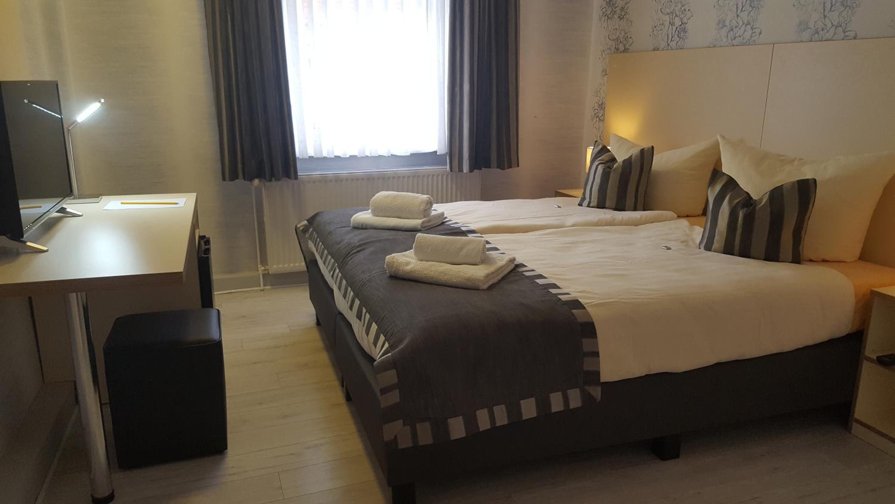 Ein Hotelzimmer mit zwei Betten, einem Schreibtisch und einem Computer.