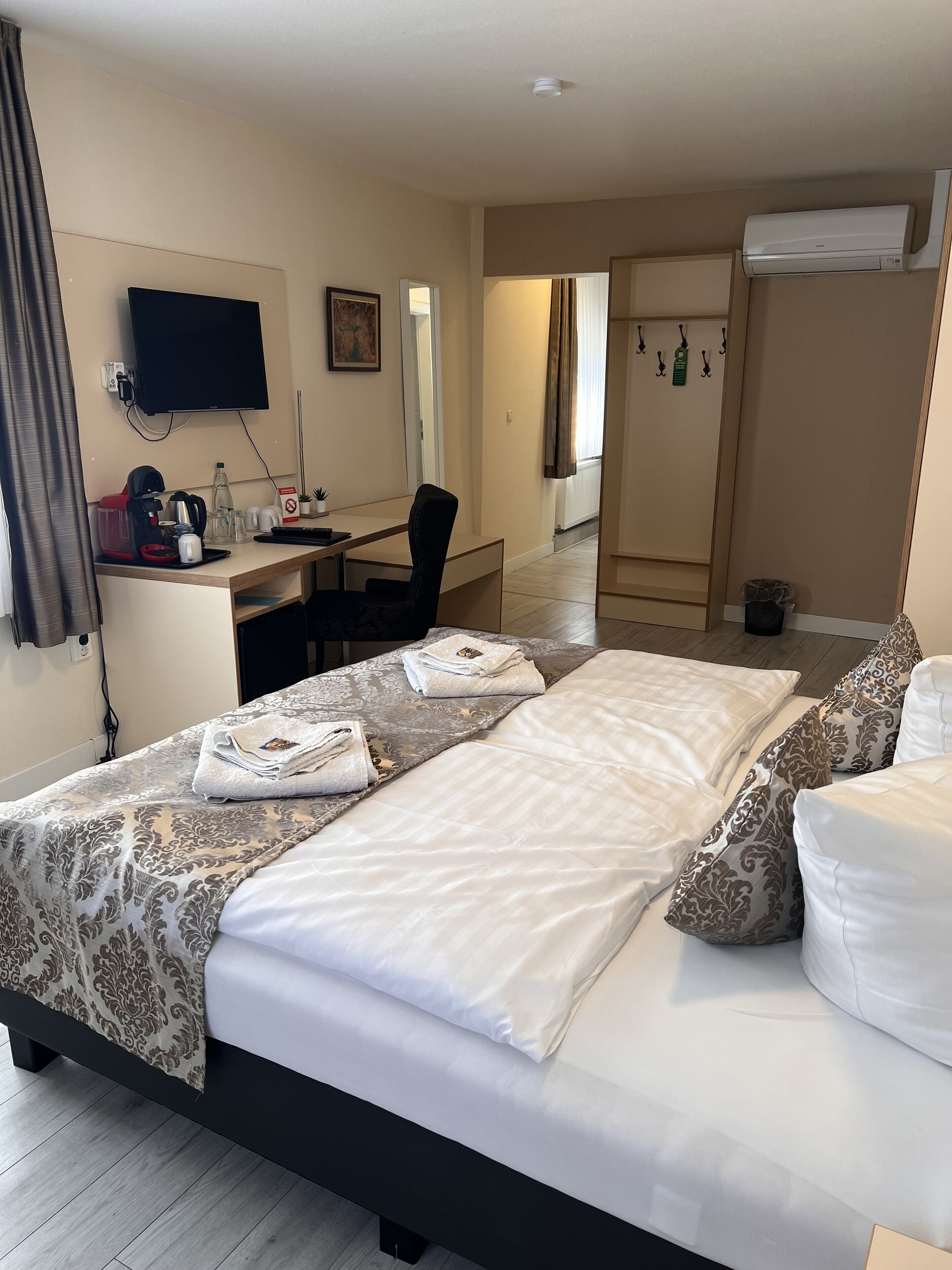 Een hotelkamer met een bed, een bureau, een televisie en een airconditioning.