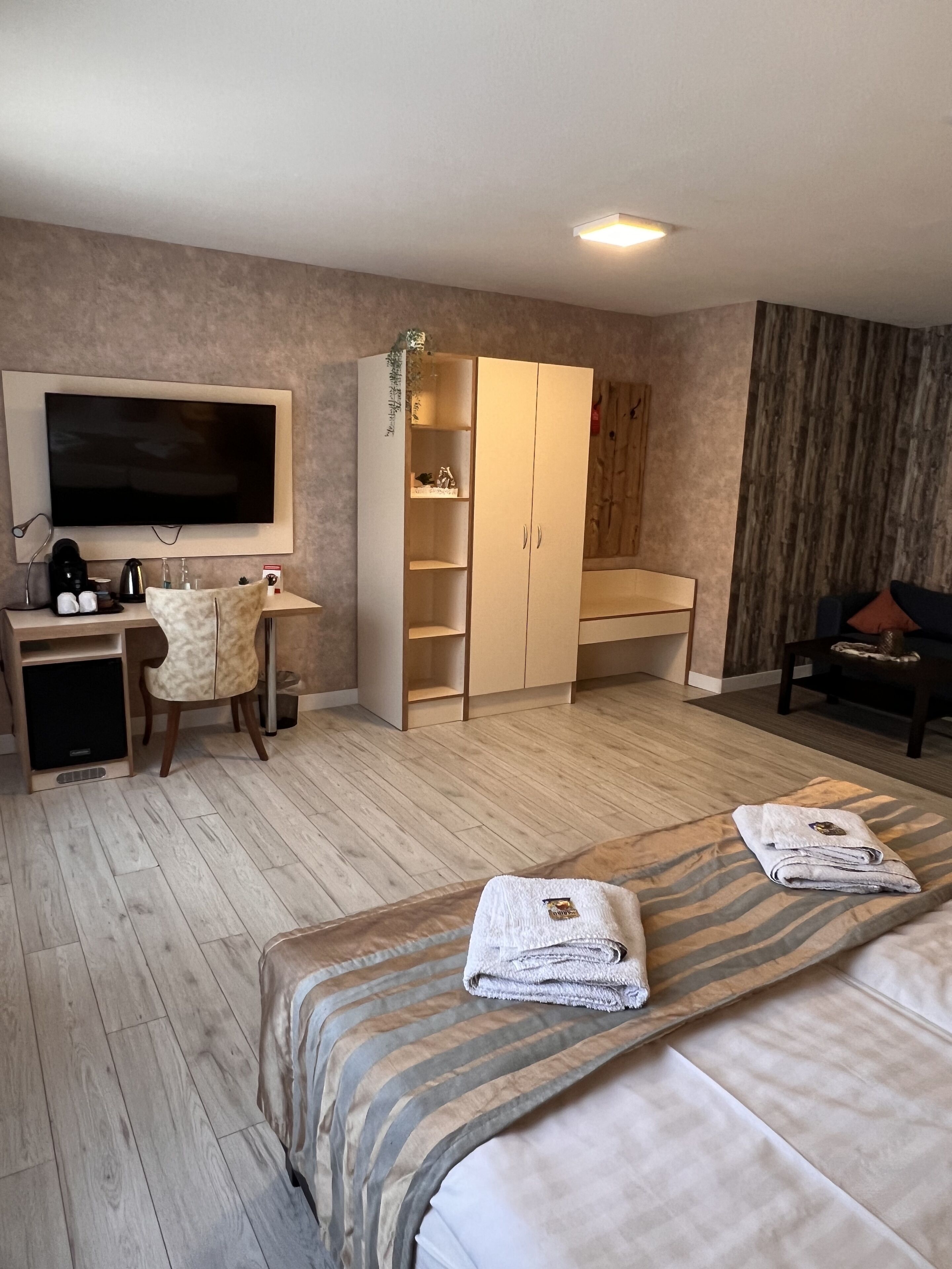 Ein Hotelzimmer mit Bett, Schreibtisch mit Fernseher, Kleiderschrank und Stuhl.