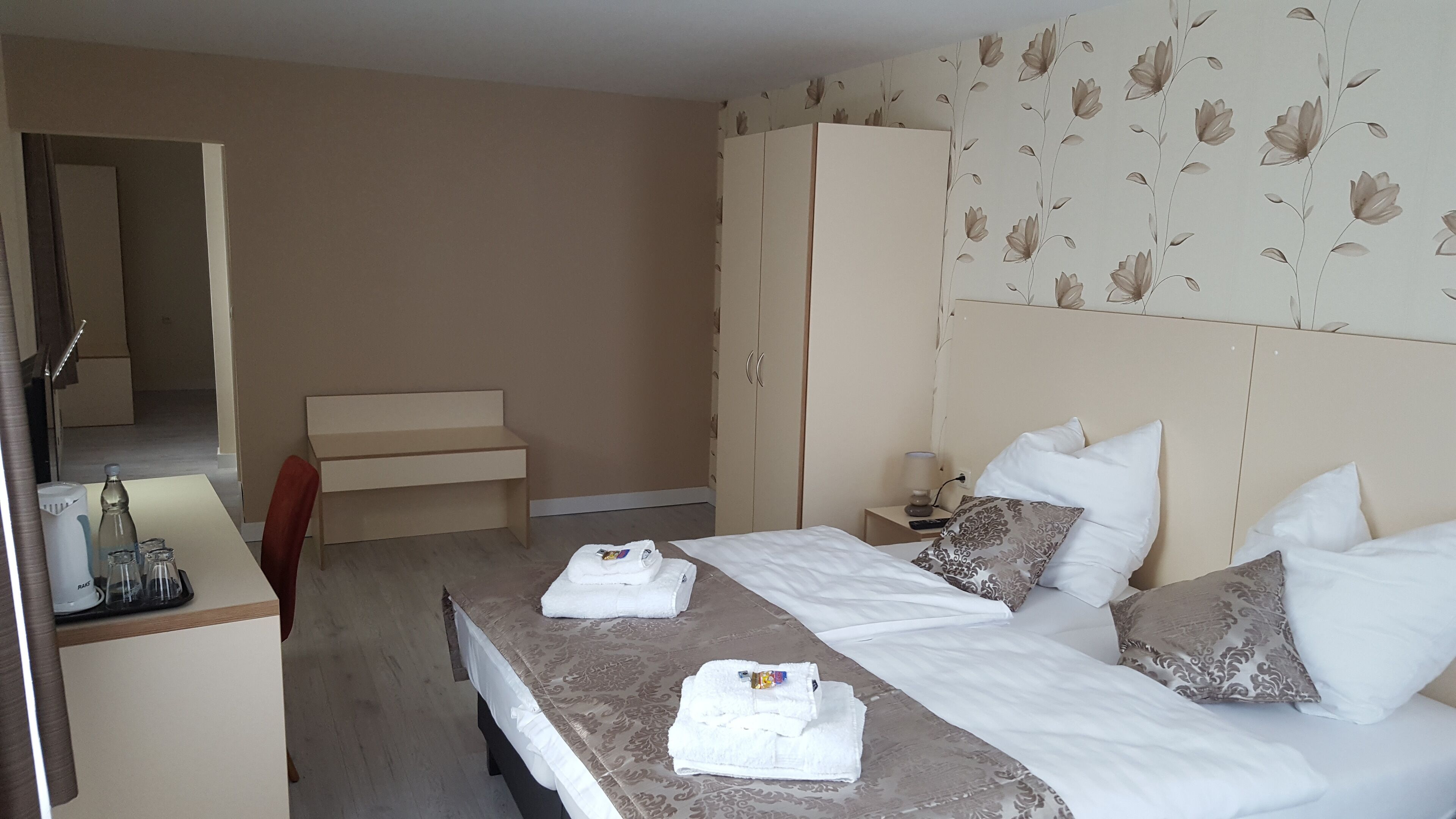 Una habitación de hotel con cama, mesitas de noche, un escritorio y un armario.