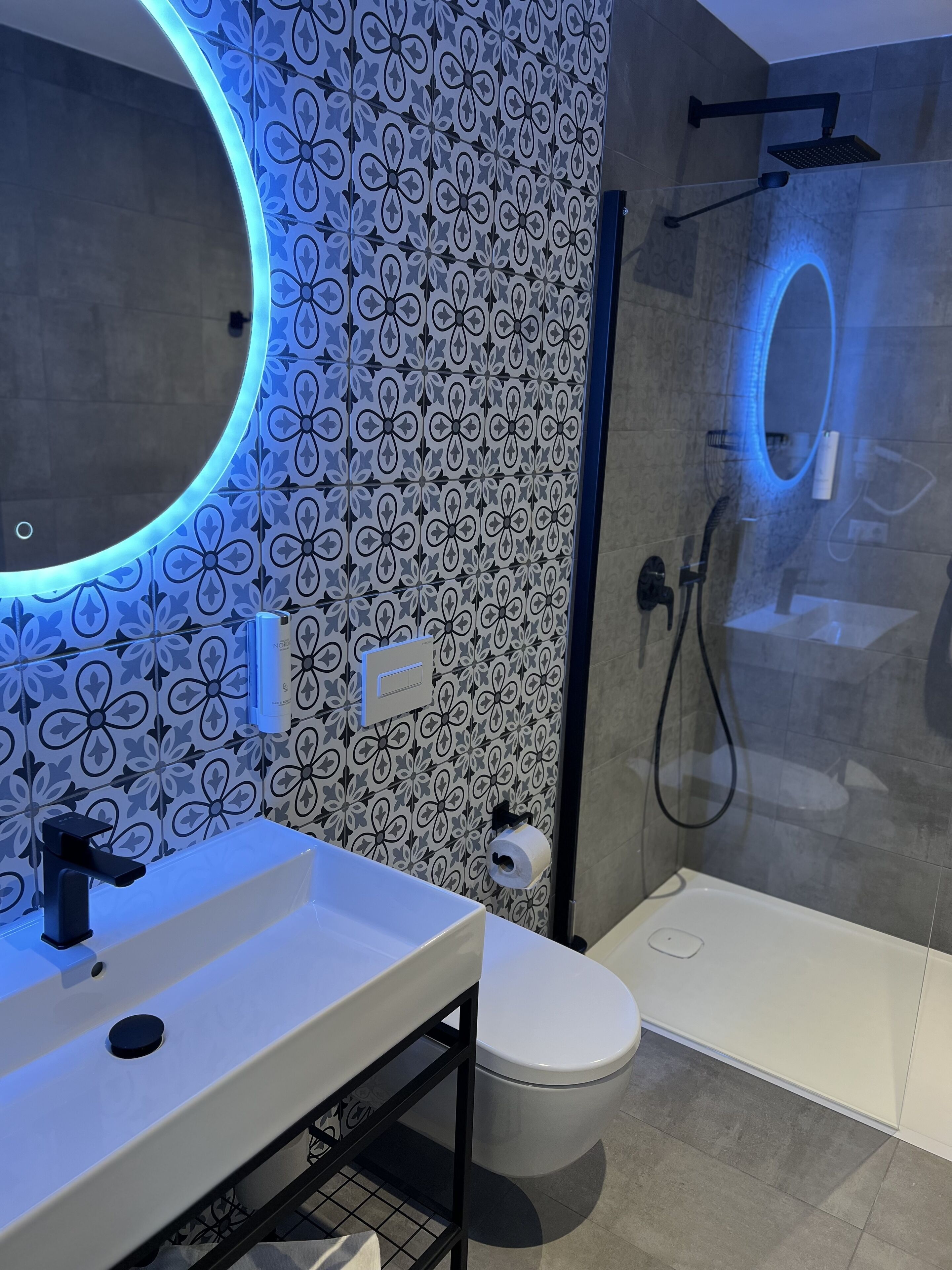 Een moderne badkamer met een wit wastafelmeubel, toilet en douche.