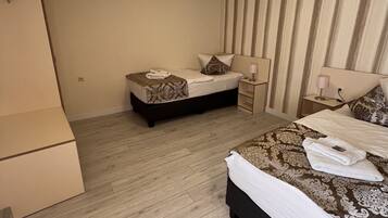 Habitación de hotel con dos camas, piso de madera, una lámpara en el techo y pared a rayas.