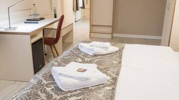 A hotel room with a bed, a desk, a chair, a TV, and a wardrobe.