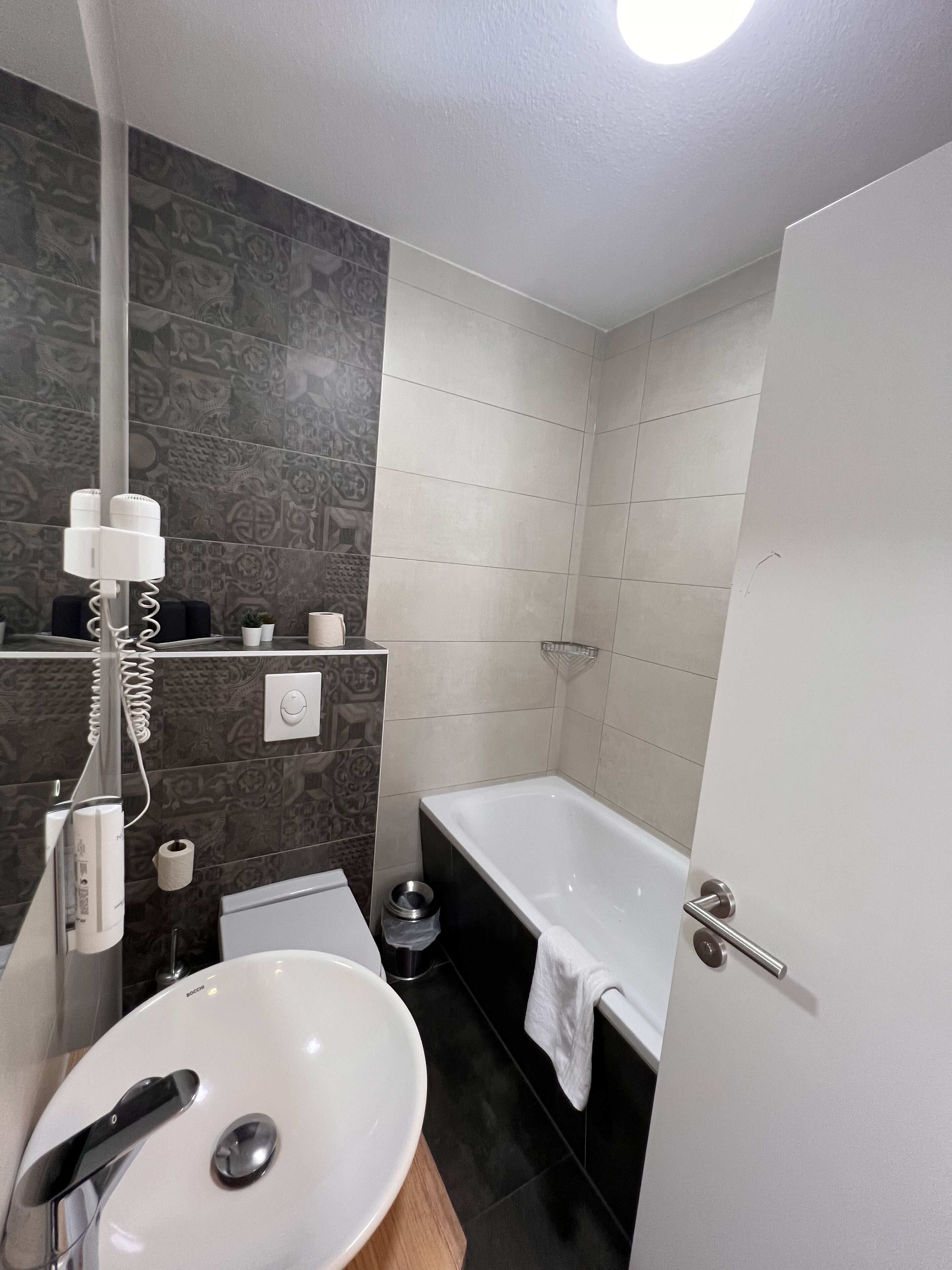 A modern bathroom with a white sink, a bathtub, and a shower.