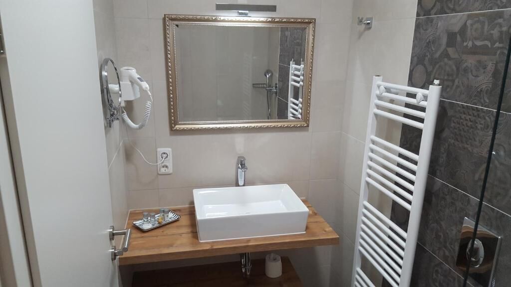 A bathroom with a white sink, a mirror, a towel rack, and a shower area.
