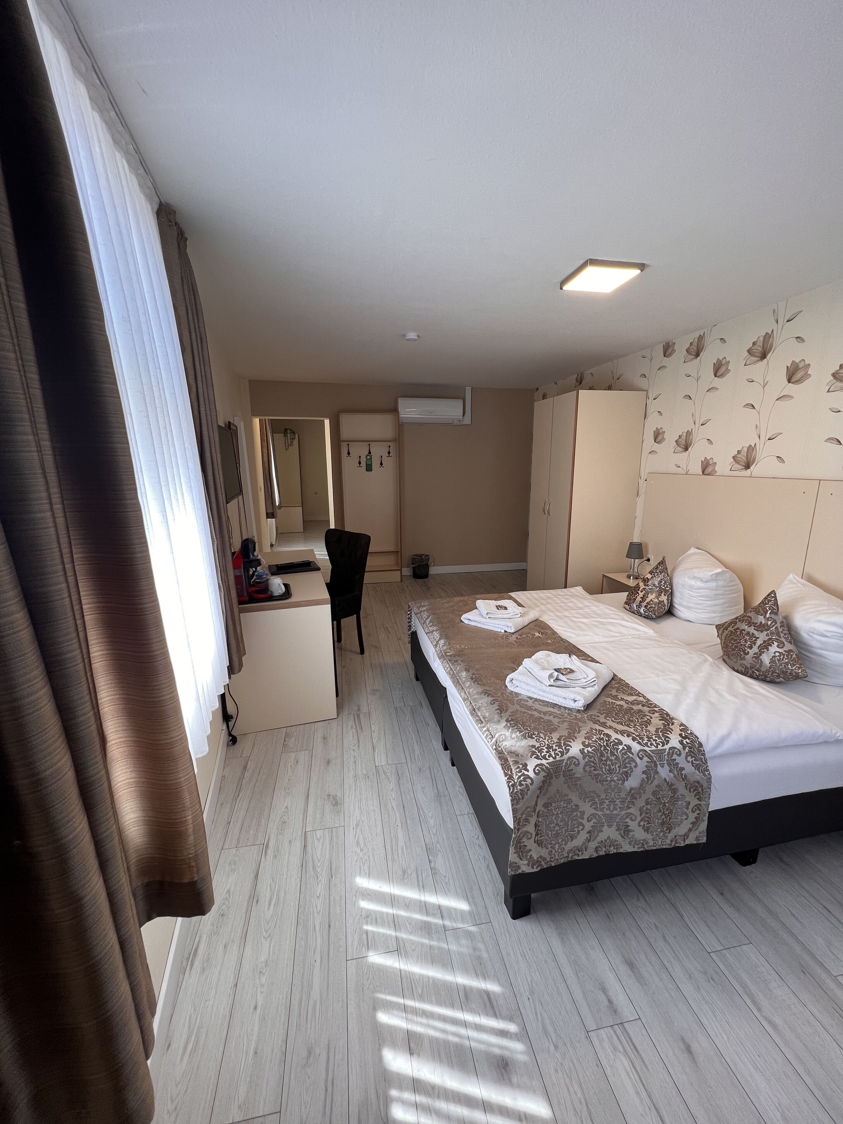 Quarto de hotel com cama, mesa de cabeceira e escrivaninha com cadeira.