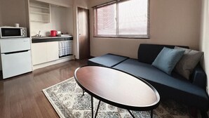 Um espaço de estar compacto com cozinha compacta, sofá e mesa de centro.