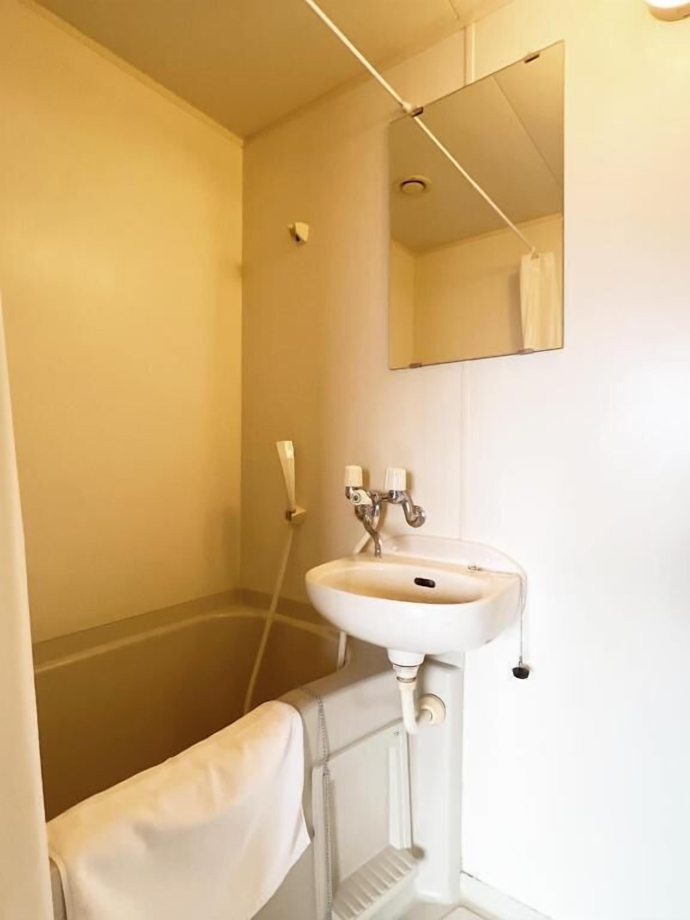 A small bathroom with a white sink, a mirror, and a shower.