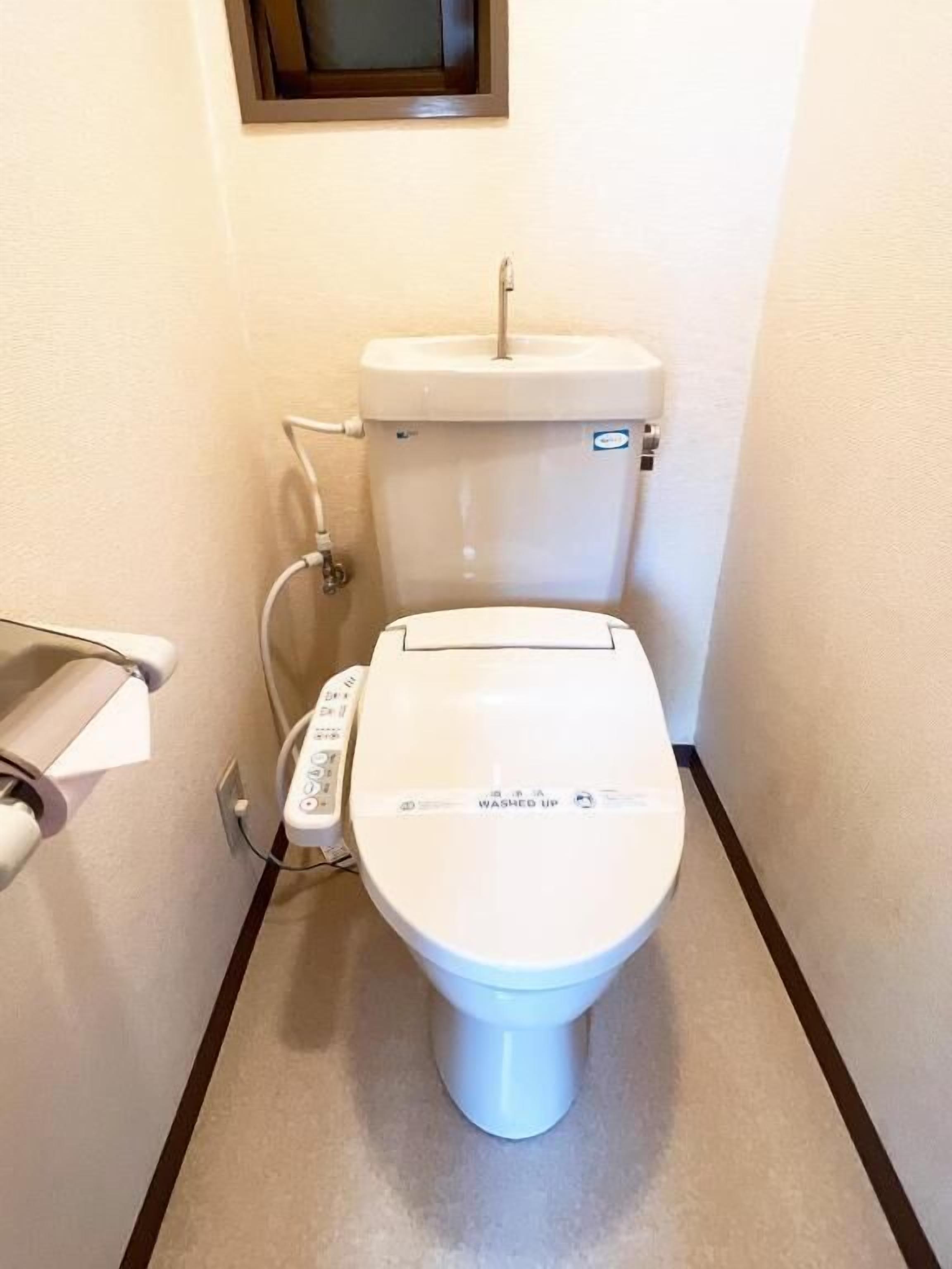A white toilet with a control panel and a bidet attachment.