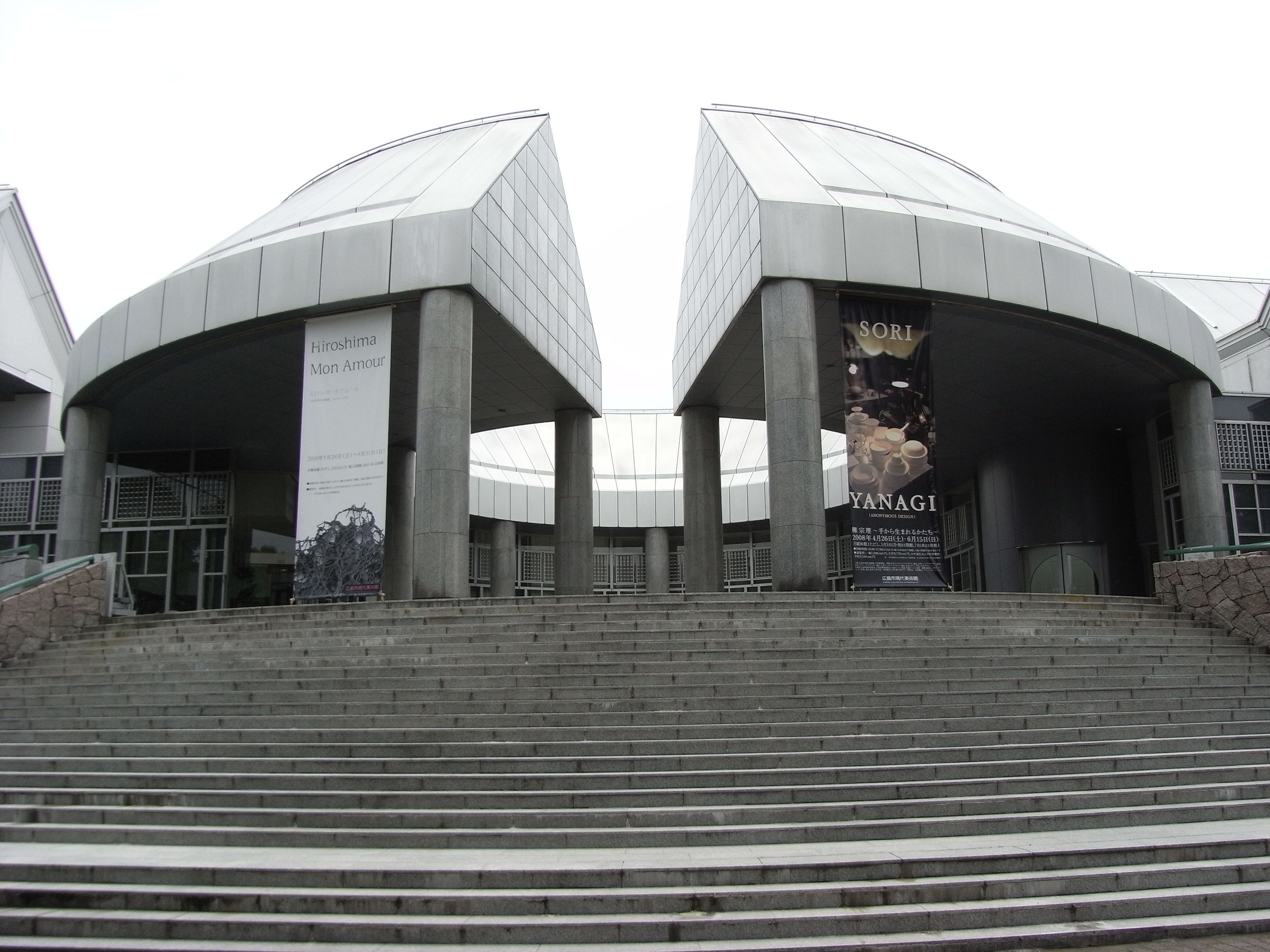 Un bâtiment moderne à l’architecture symétrique, doté d’un espace central ouvert et d’un escalier menant à l’entrée.