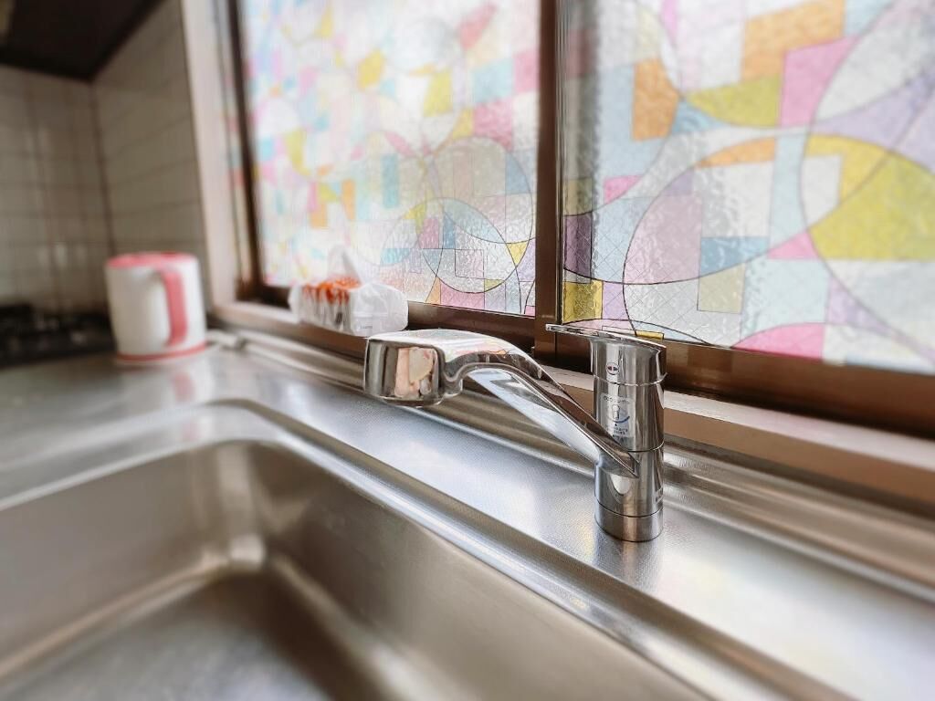 Un lavamanos de cocina con un grifo moderno y una ventana con vidrieras de colores.