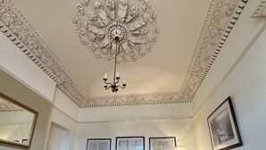 A living room with a fireplace, a chandelier, a sofa, a television, and framed certificates on the wall. - Watermead House (Chard)