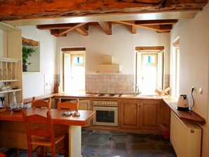 A kitchen with wooden cabinets, a stone floor, and a built-in oven.