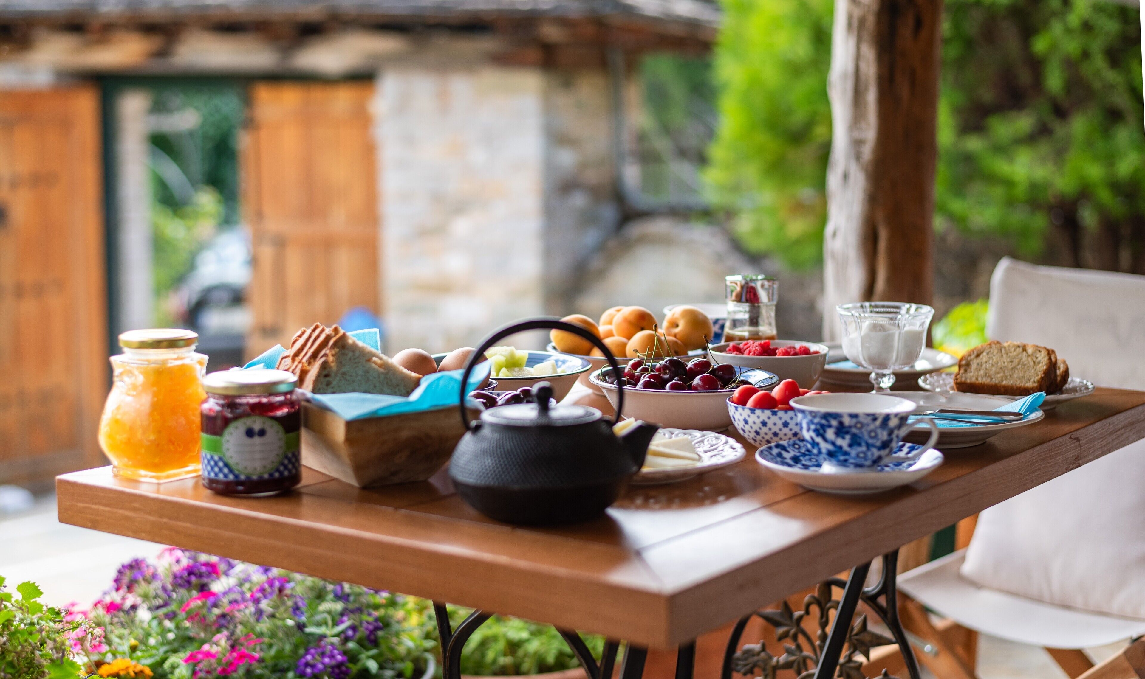 A breakfast table with various food items, a teapot, and a cup of milk.