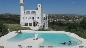 Una piscina al aire libre, sillones reclinables de piscina