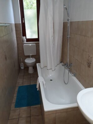 A bathroom with a bathtub, toilet, and shower. - Pension Donau Apartments (Hannover)