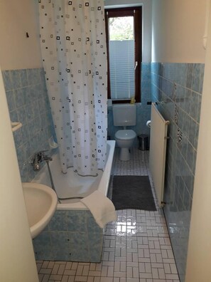 A bathroom with a bathtub, toilet, and sink.