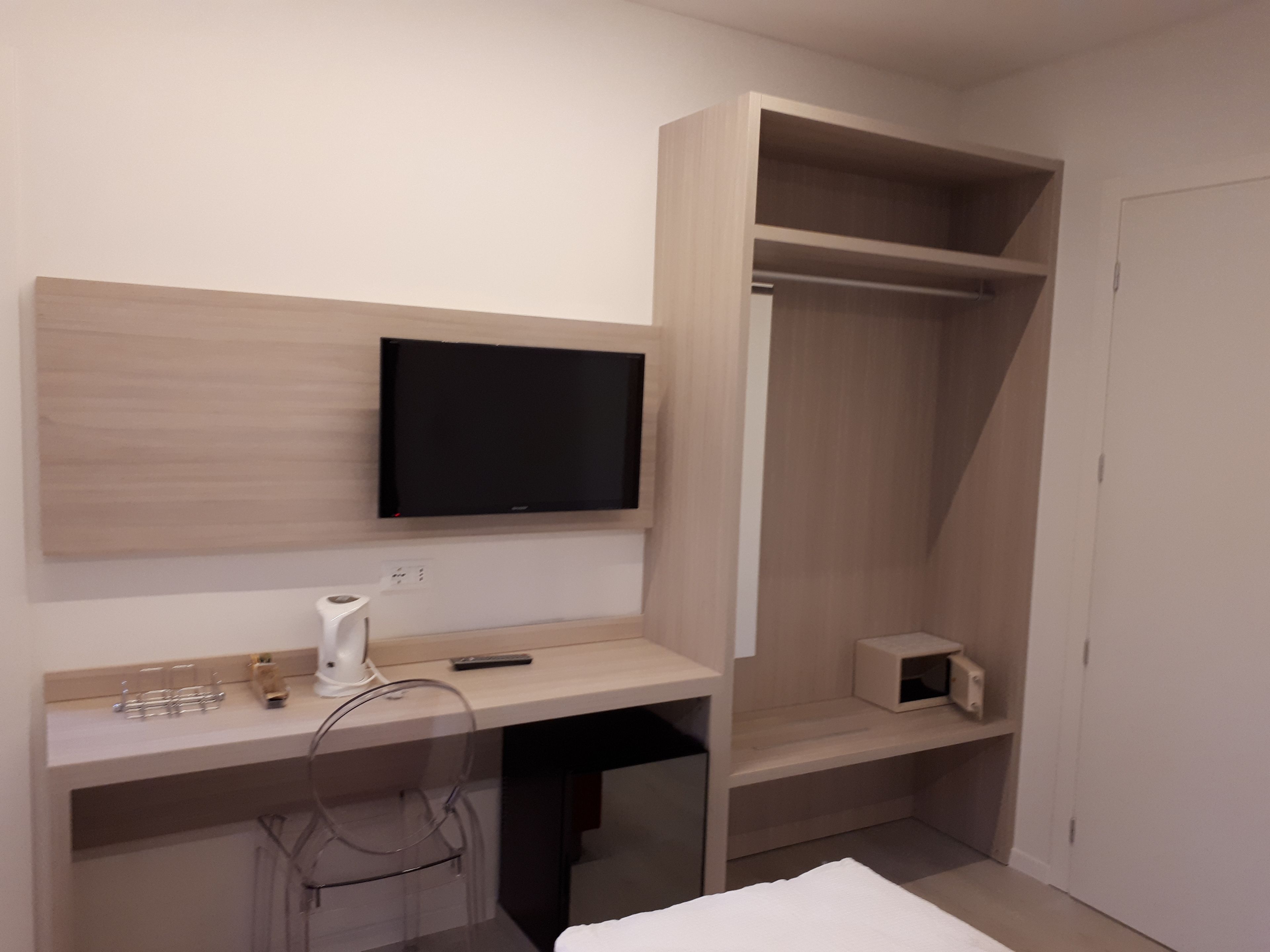 A modern bedroom with a built-in desk, a television, and a wardrobe.
