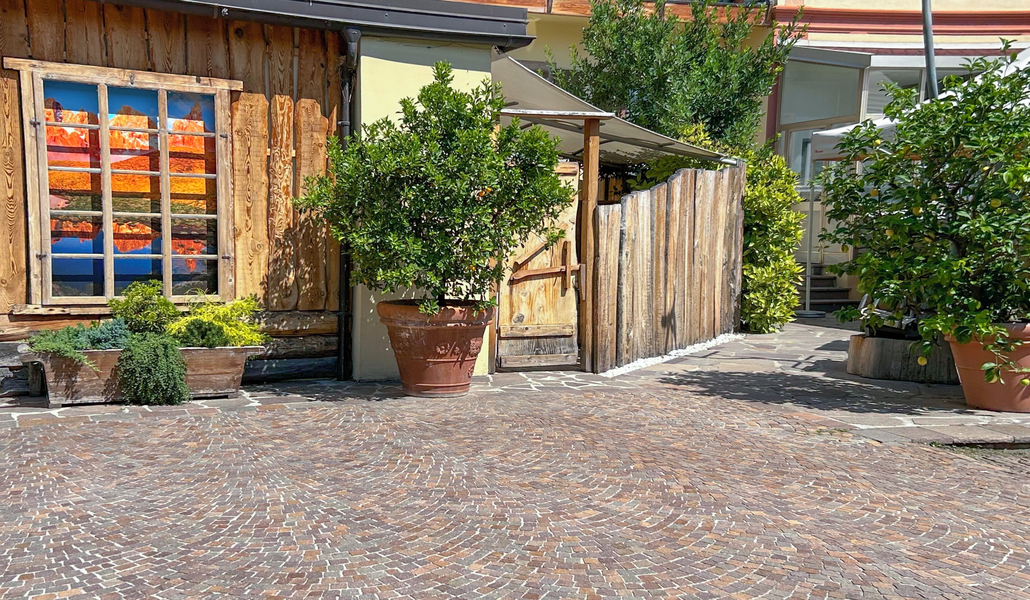 Un patio con suelo de piedra, vallas de madera y plantas en macetas.
