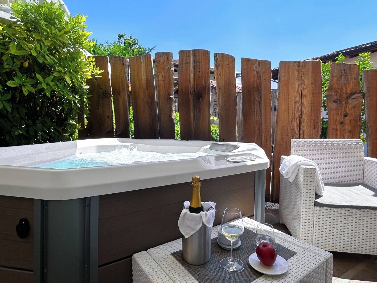 Un bain à remous avec une bouteille de champagne, deux verres et une pomme sur une table.