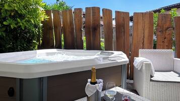 Un bain à remous avec une bouteille de champagne, deux verres et une pomme sur une table.
