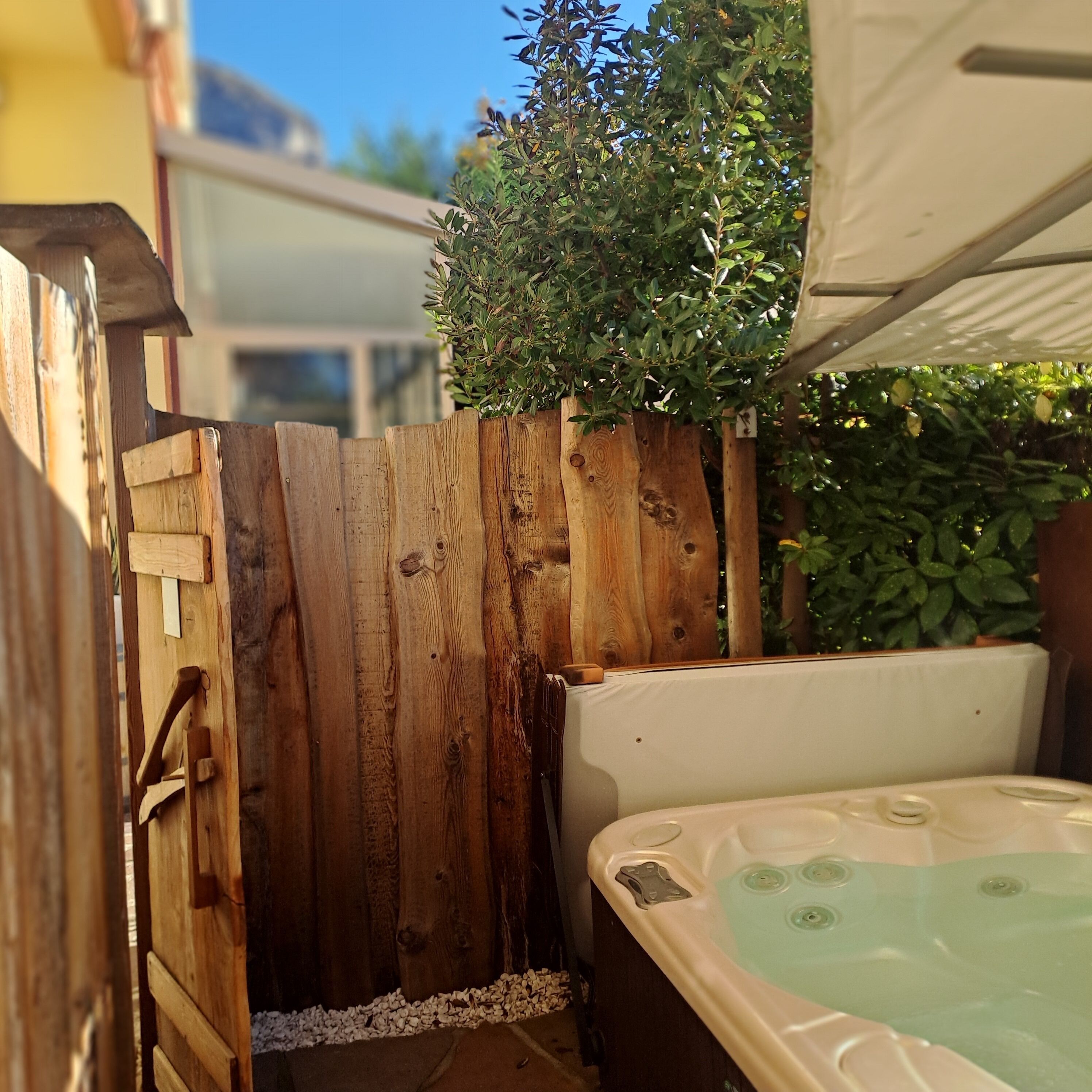 Ein Holzzaun mit Whirlpool und einem kleinen Garten.