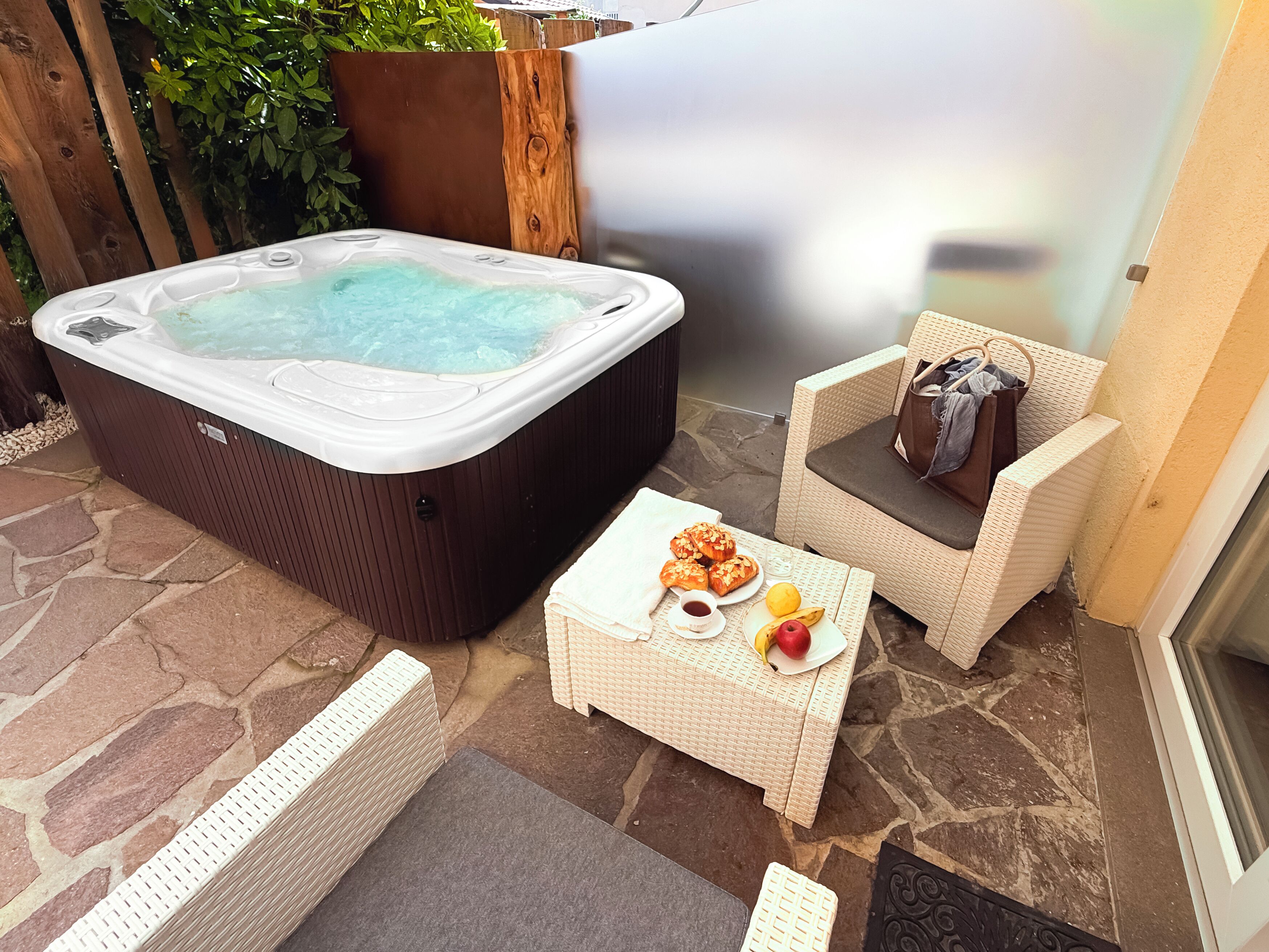 A hot tub, wicker furniture, and a small table with snacks and fruit.