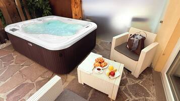 A hot tub, wicker furniture, and a small table with snacks and fruit.