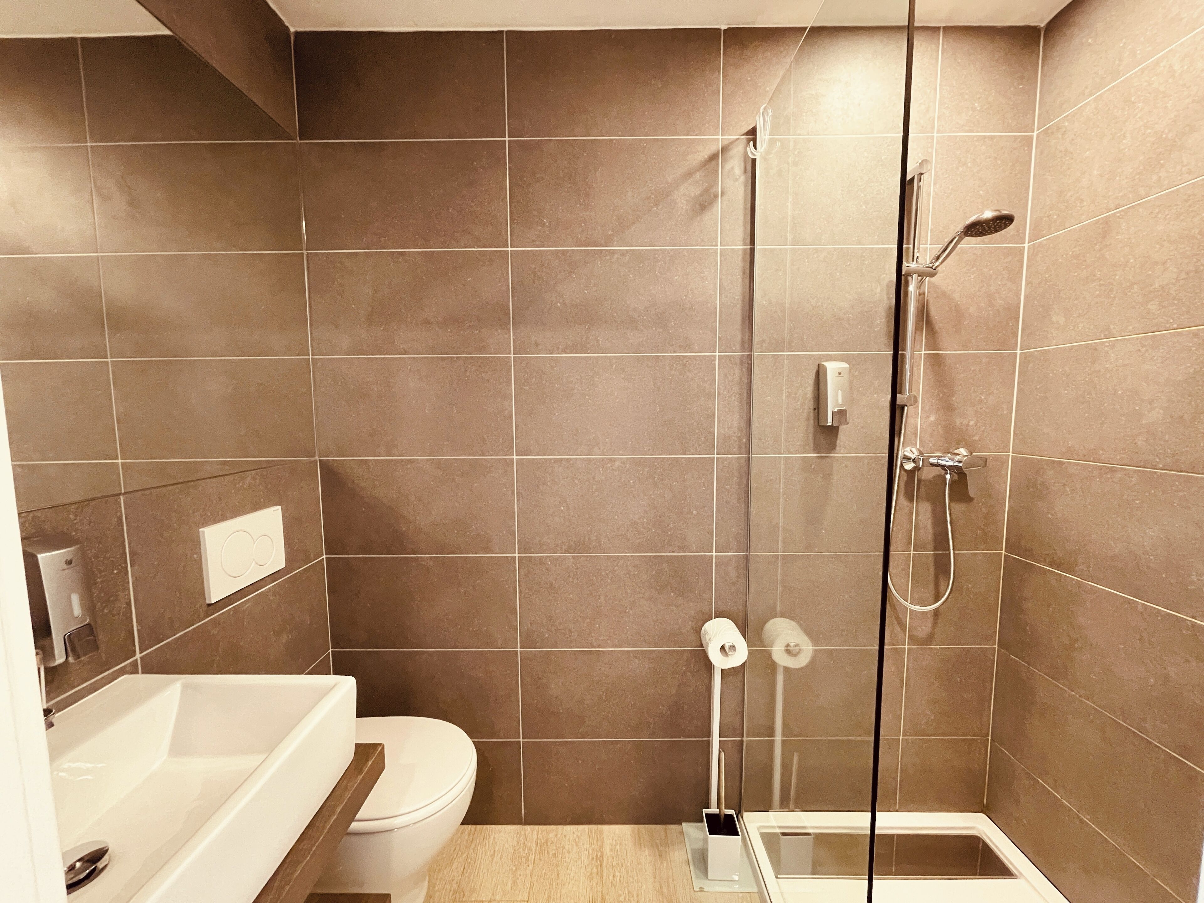 A modern bathroom with a shower, toilet, and sink.