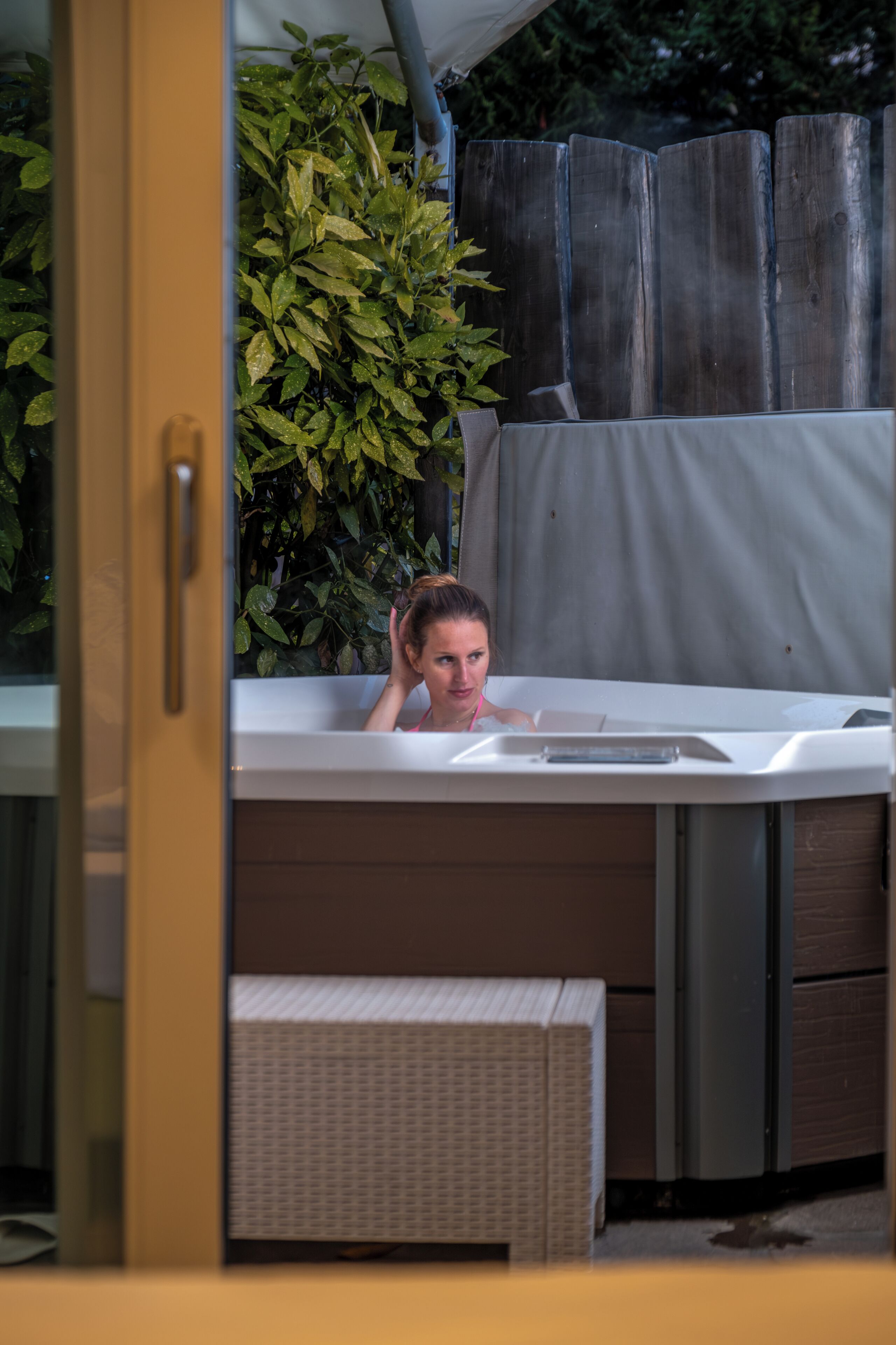 Un espace de détente avec une baignoire, un banc en osier et une clôture en bois.