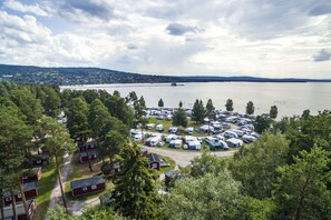 A campground with RVs and cabins surrounded by trees, near a lake with a bridge in the distance. - First Camp Siljansbadet - Rättvik  (Rattvik)