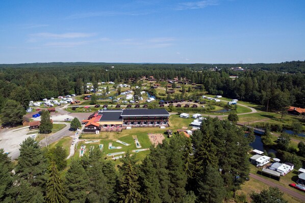 Vista aérea de un camping con vehículos recreativos, un edificio grande y un lago.