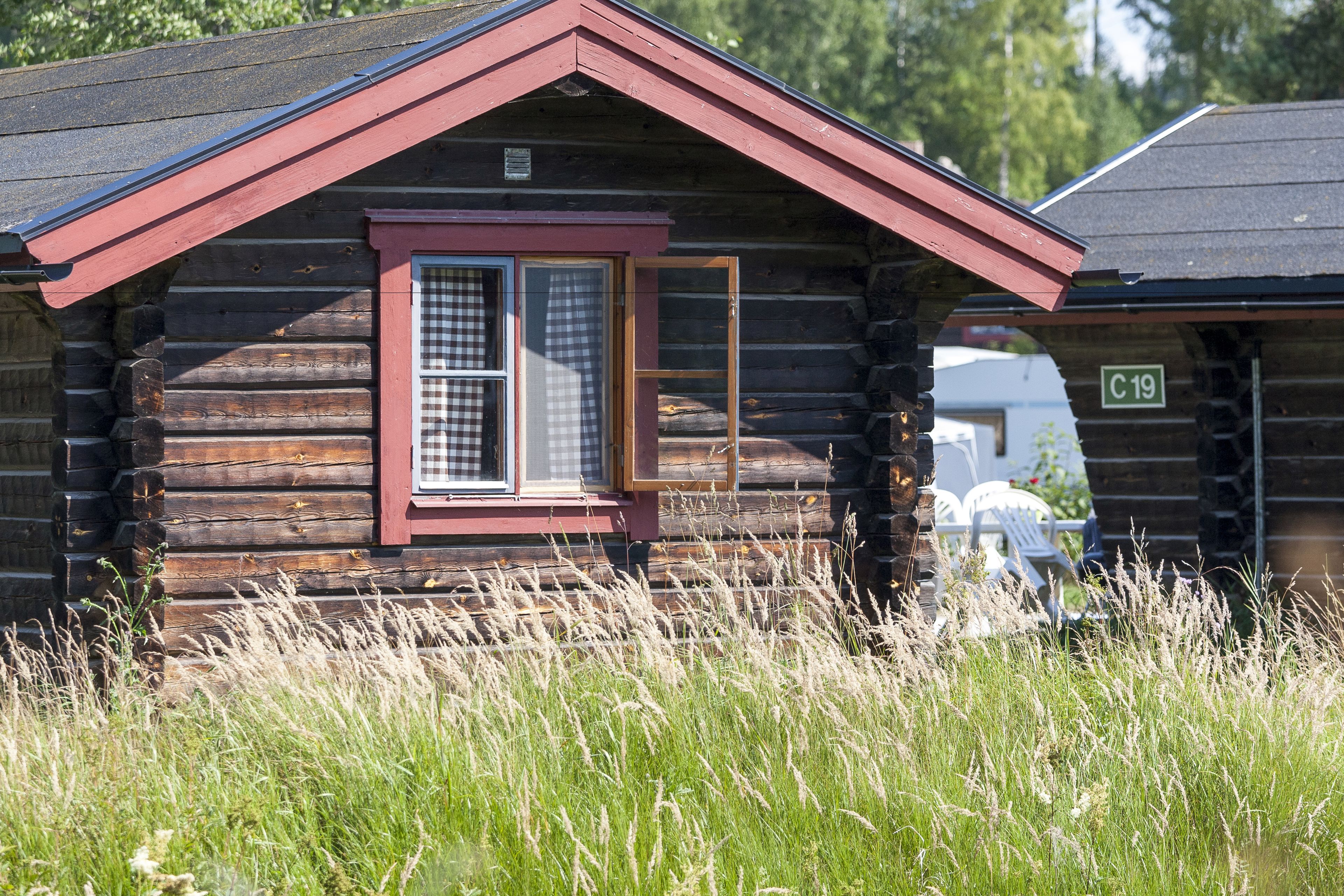 A log cabin with a checkered window and a red roof.