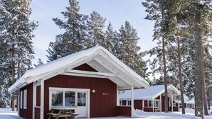 A red cabin with a white roof, a wooden bench, and a covered picnic table. - First Camp Enåbadet (Rattvik)
