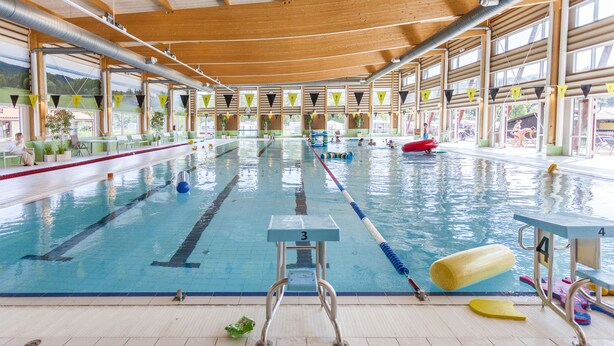 An indoor swimming pool with multiple lanes, diving boards, and a lifeguard chair. - First Camp Enåbadet (Rattvik)
