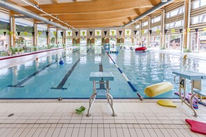 An indoor swimming pool with multiple lanes, diving boards, and a lifeguard chair. - First Camp Enåbadet (Rattvik)
