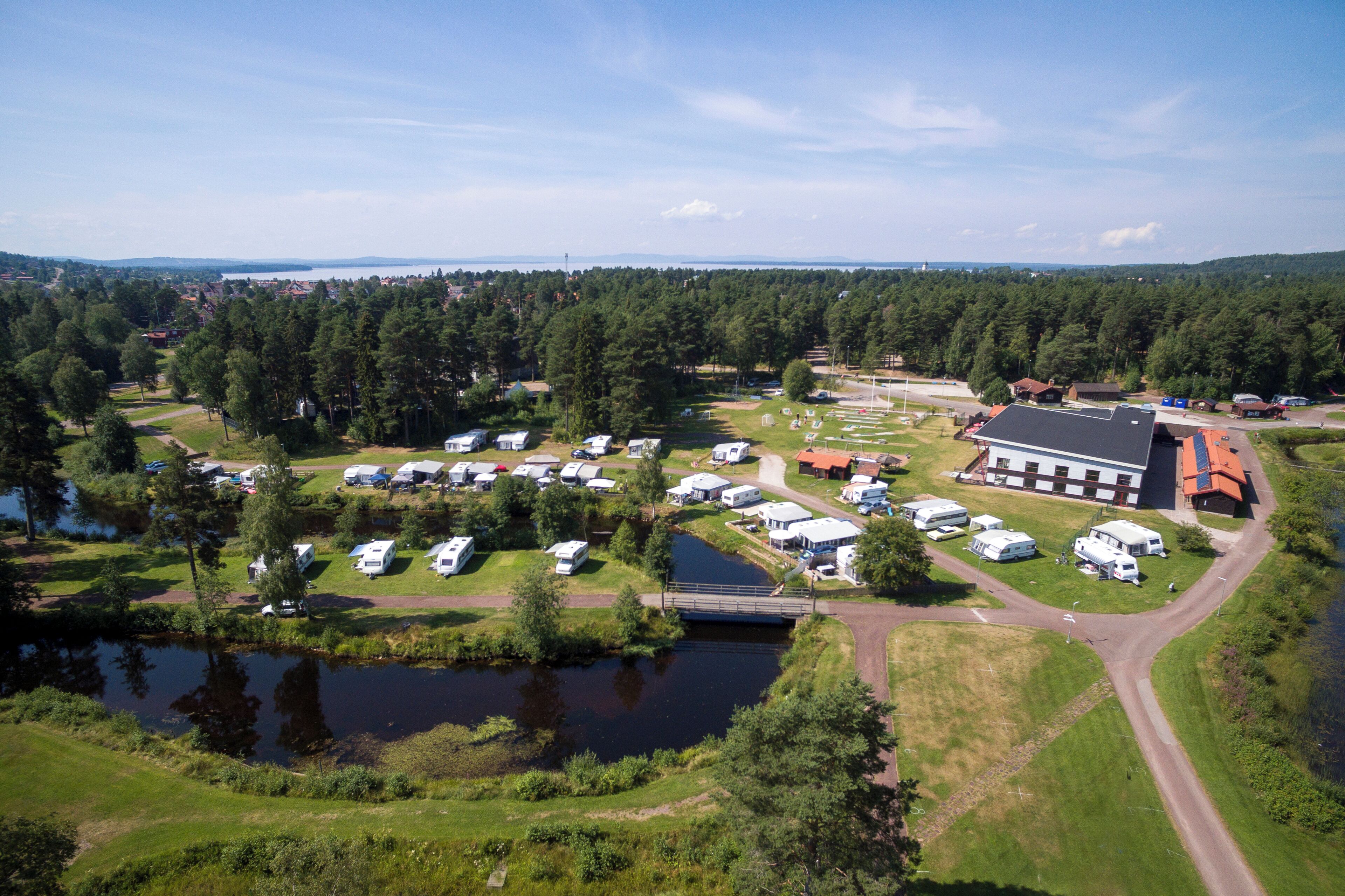 An aerial view of a campsite with RVs, a small lake, and a building with a red roof.