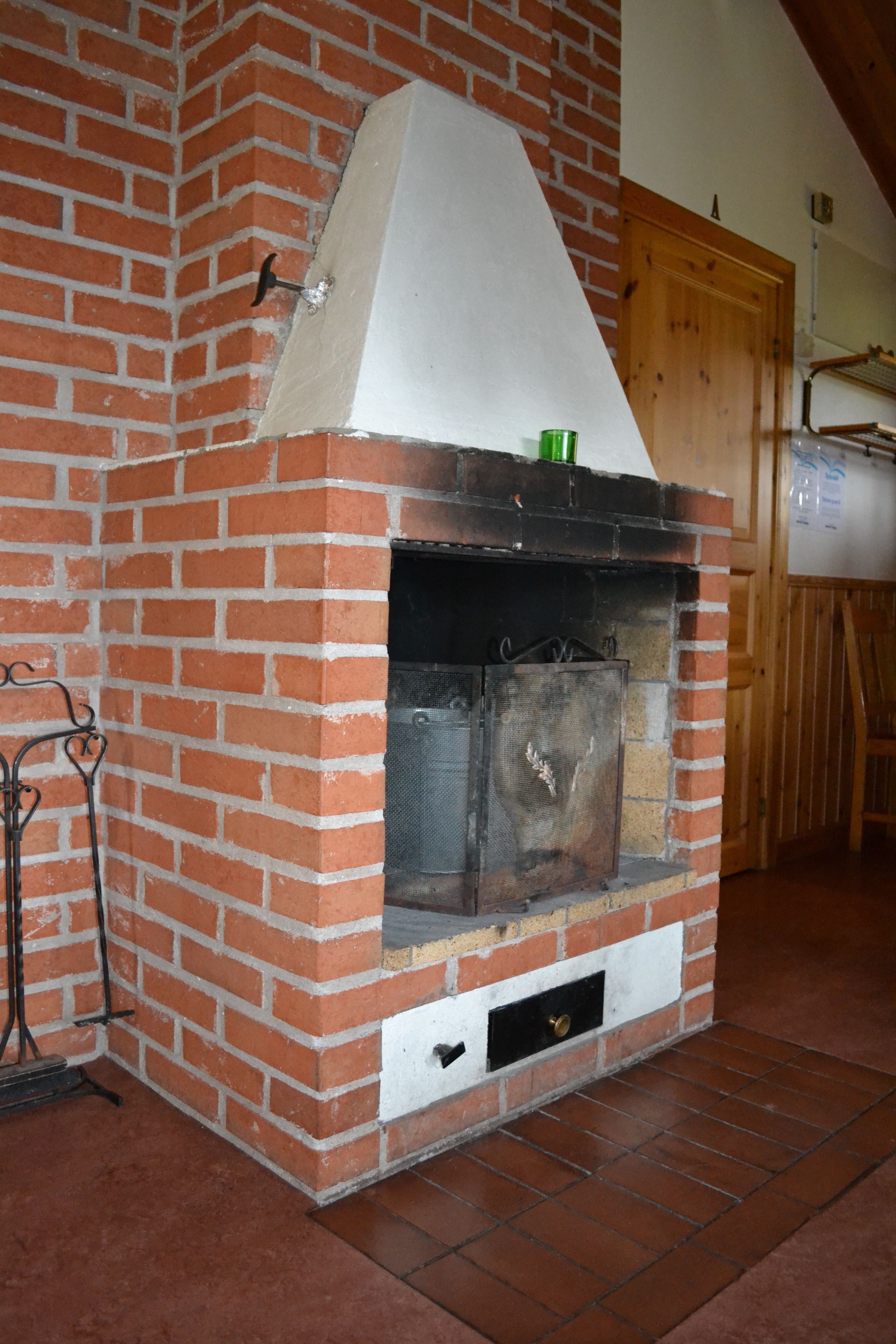 A brick fireplace with a white mantel and a metal screen door.
