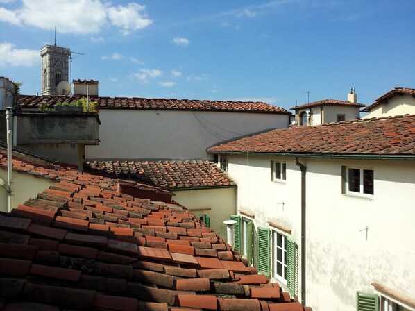 A traditional European street with terracotta-tiled roofs, a prominent tower, and a staircase leading to a higher level.