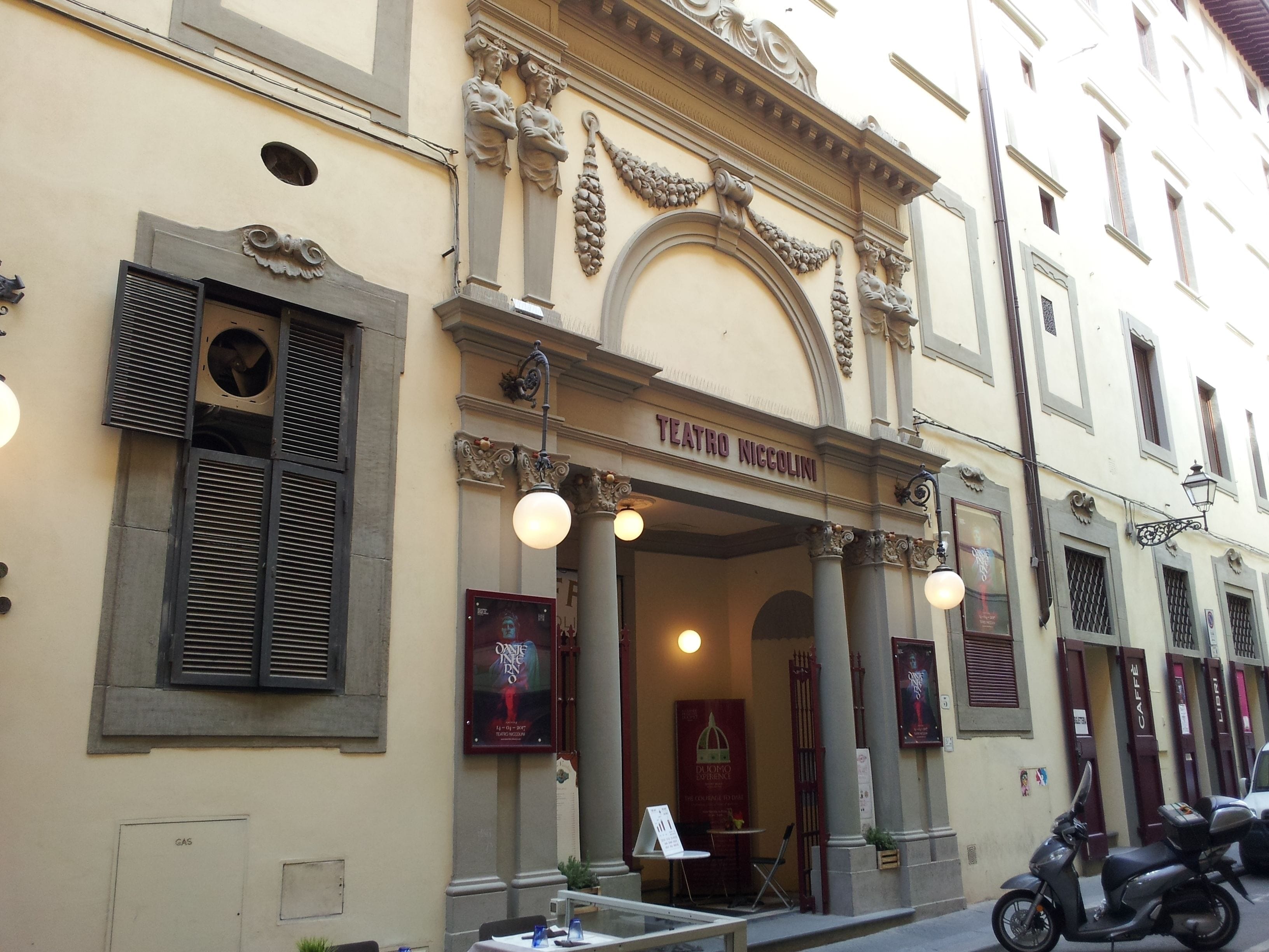 Teatro Niccolini with ornate architectural details, a signboard, and a parked scooter.