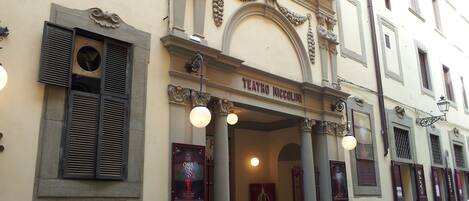 Teatro Niccolini with ornate architectural details, a signboard, and a parked scooter.