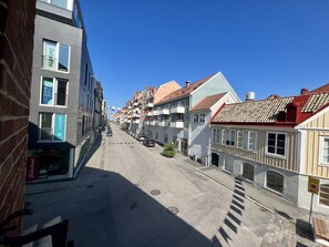 Una calle estrecha flanqueada por edificios de varios pisos, algunos con balcones y letreros de negocios como Deloitte y Xperisite.