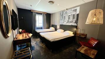 A hotel room with two beds, a desk, a chair, and a large window.