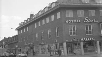 A historic hotel with a classic facade, featuring a prominent sign for HOTEL Siesta and CITY HALLEN.