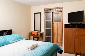 Une chambre d’hôtel avec deux lits, un bureau, une télévision et une armoire.