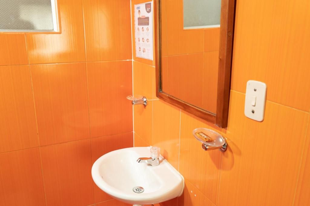Une salle de bain avec un lavabo blanc, un miroir et un distributeur de savon liquide.