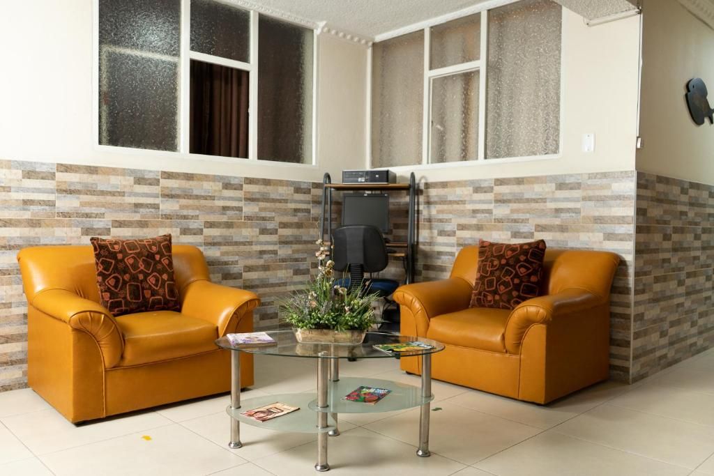 A room with two leather sofas, a glass coffee table, and a television on a stand.