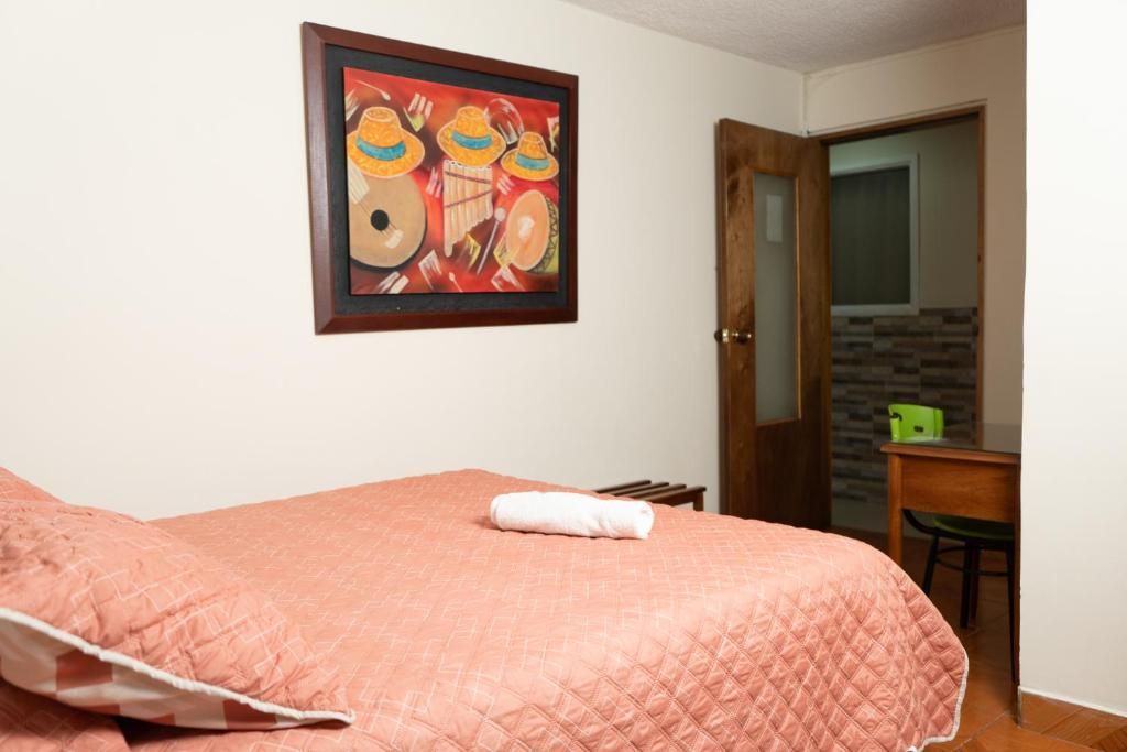Un dormitorio con una cama, un cuadro, un escritorio y una silla.