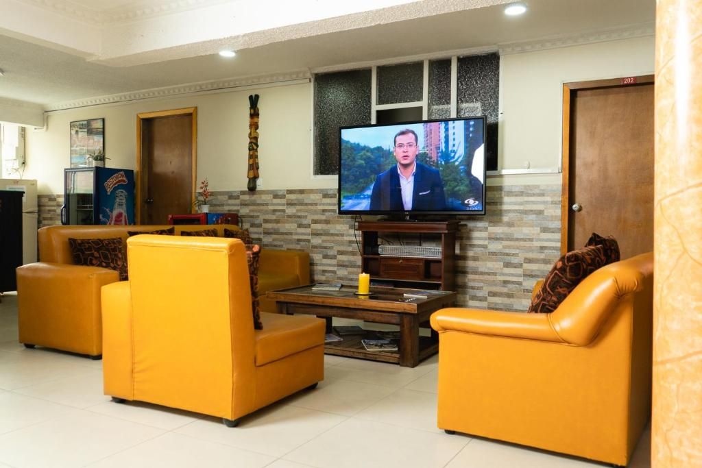A living room with yellow sofas, a flat-screen TV, a coffee table, and a fireplace.