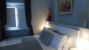 A neatly made bed with white linens, a headboard, and a bedside table with a lamp. - Room Inn Vatican (Rome)